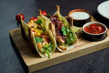 Appetizing Mexican tacos with fried chicken and stewed beef, cabbage, onions and parsley in special stands. Traditional mexican cuisine