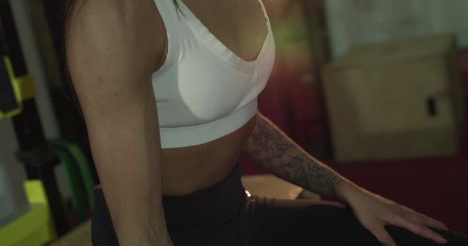 View of unrecognizable sports girl trains arm muscles with dumb-bell in gym