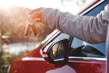 Young woman holding car keys in hand. Happiness of buying the first car. 