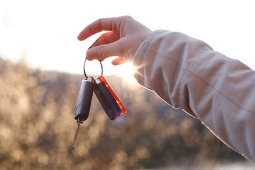Young woman holding car keys in hand. Happiness of buying the first car. 