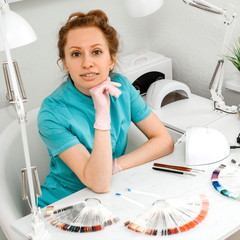Manicurist at work in the office. Drawing gel polish on tips, creating a picture. Equipment and inventory of a manicure cabinet.