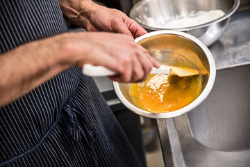 Close up of man's hands whisking eggs in the bowl. Preparing mixture in the kitchen.