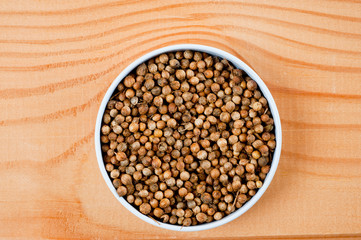 Coriander grains shot large on a wooden background. Background for spices and cuisine.