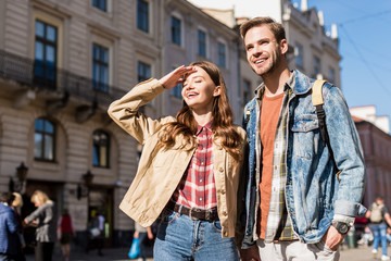 Girlfriend covering face from sunlight and boyfriend smiling in city