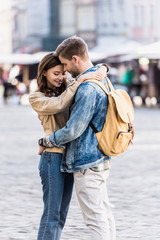 Man with backpack hugging with beautiful girlfriend in city