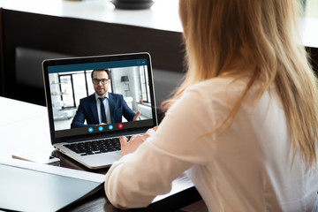Fototapeta na wymiar Back view of young businesswoman talk with male business partner using video call on modern laptop, female employee speak consult with businessman on webcam conference, online consultation concept