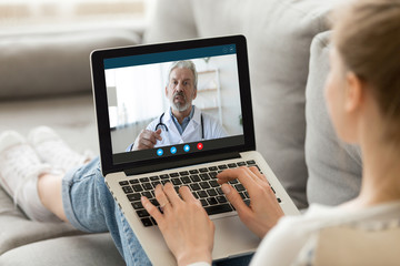 Young woman sit on couch at home have video call with doctor use wireless internet connection on...