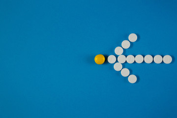 arrow of white pills on a blue background