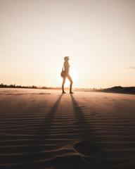 Fototapeta na wymiar Silueta chica con sol en el atardecer en la arena