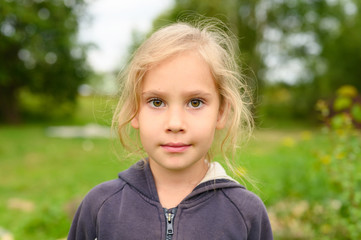 portrait of a cute little six year old european girl on the background of nature outdoor