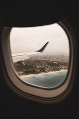 Vistas desde ventana avión con alas y paisaje de playa