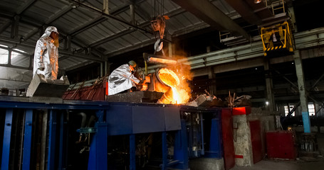 Smelting orange metal in a metallurgical plant. Liquid iron from the ladle