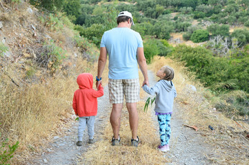 A father with his two children in nature. the family has a fun summer vacation traveling through the mountains of the island of Crete