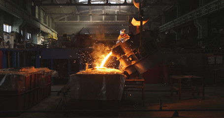 Smelting metal in a metallurgical plant. Liquid iron from metal ladle pouring in castings at factory