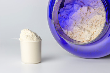 Scoop with protein and a can on light background close-up, concept of sports nutrition.