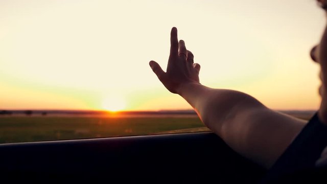 A Young Girl Put Her Hand Out Of The Car Window At Sunset. Close Up.Slow Motion.