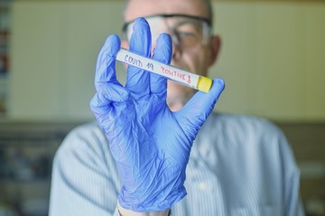 The sample of Covid 19 in the test tube. Doctor - epidemiologist holding thesample tube with sample of coronavirus.