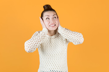 the girl covers her ears with her hands and looks up with displeasure