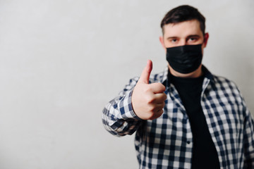 man in a shirt in a black medical mask on a gray background