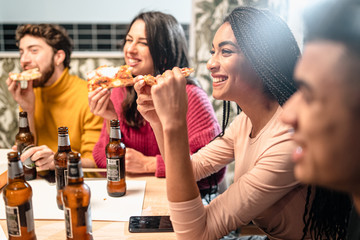 Trendy friends eating pizza. Young people from different races having a party at home. Food lifestyle concept.