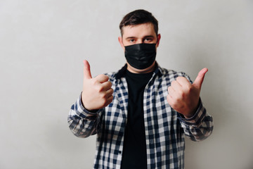 man in a shirt in a black medical mask on a gray background