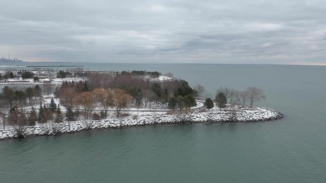 Aerial flying over snowy Lakefront Promenade Park and revealing Downtown Toronto on background