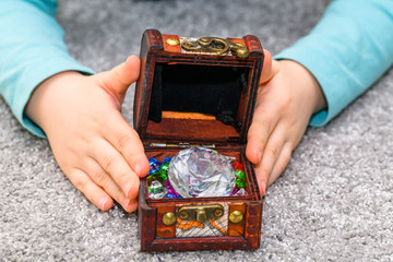 Five year old boy holding a treasure chest full of multicolored gems in his hands
