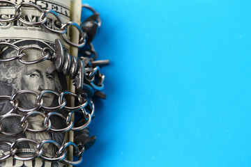 Dollar wrapped in a chain on a blue background with place for an inscription or text