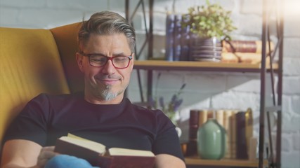 Older white man in glasses reading at home