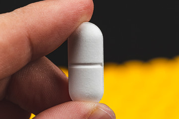 close up view of a hand holding a white pill - health care concept