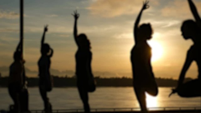 silhouette asian people practicing yoga pose , exercise outdoors with view of beautiful lake - relax in nature