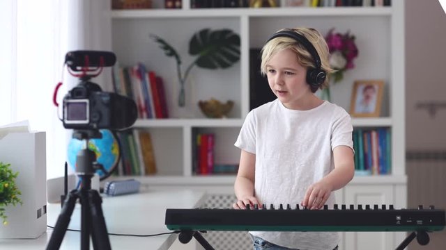 young boy performing and recording vlog from home, playing music on digital keyboard panel