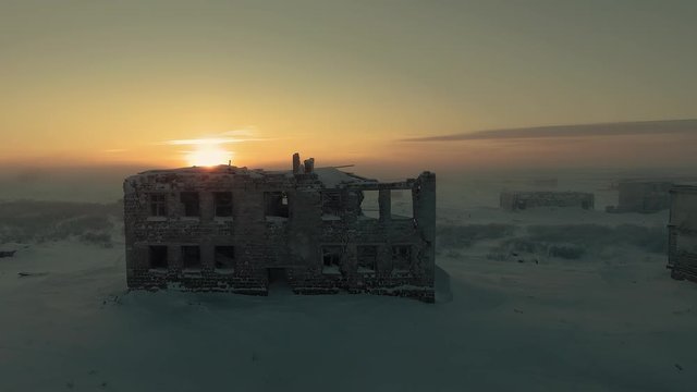 The sun on the edge of a ruined house