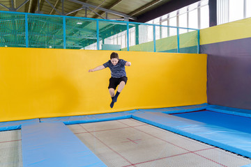 Overweight cute little boy jumping on trampoline indoors in a sport center for kids