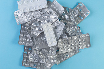 A pile Used blister packs of pills on blue background