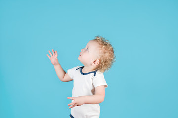 Two-year-old curly-haired baby girl reaches for something, turning sideways