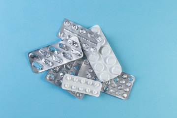 A pile Used blister packs of pills on blue background.