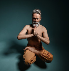Obraz premium Old man with grey beard doing yoga, pilates, fitness training, stretching exercise, asana levitates or balance workout on floor