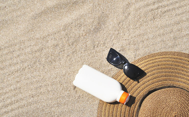 Fototapeta na wymiar Summer time. Hat and sun protect cream on sand texture.