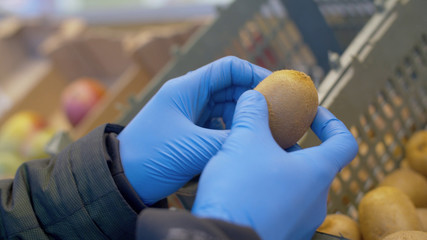 Male hand choosing kiwi in the supermarket