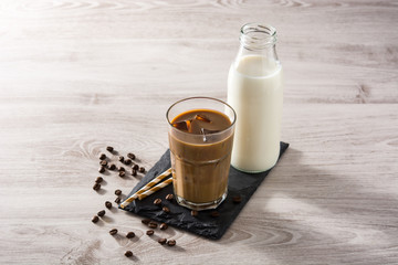 Iced coffee or caffe latte in a tall glass on white wooden table