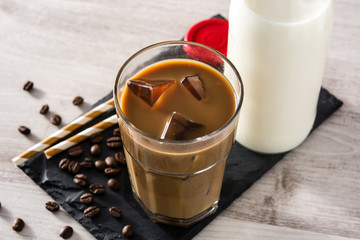 Iced coffee or caffe latte in a tall glass on white wooden table