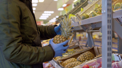 A man choosing pineapple in the supermarket
