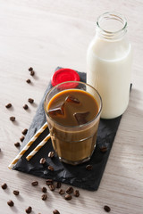 Iced coffee or caffe latte in a tall glass on white wooden table