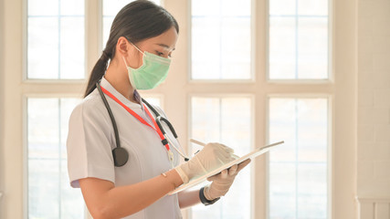 Cropped shot of Nurse wearing gloves using tablet to record covid-19 virus infected person.