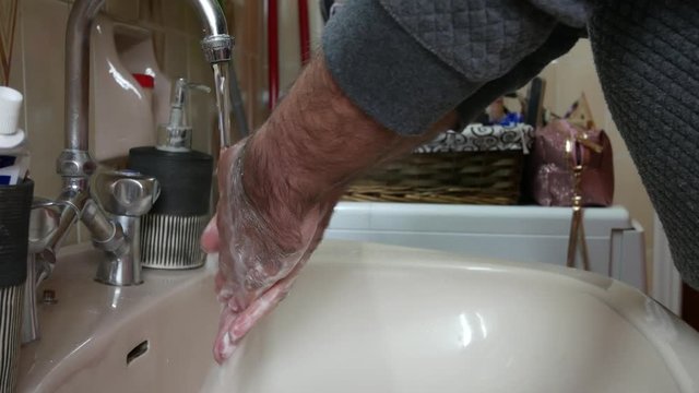 Man in quarantine washing his hands in a sink. Covid-19 pandemic precautions. Static shot.