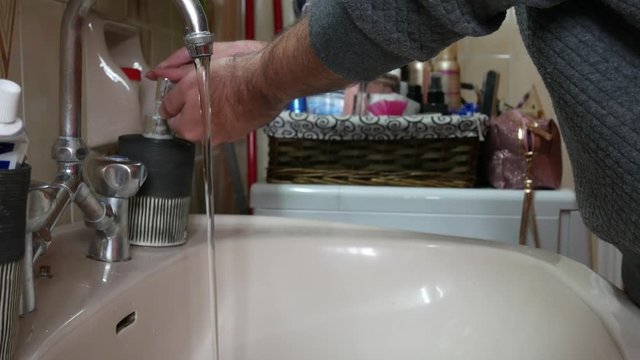 Washing hands in a sink. Man in quarantine during Covid-19 pandemic. Static shot.