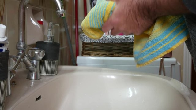 Man in quarantine wiping his wet hands with a towel after washing. Covid-19 pandemic precautions. Static shot.