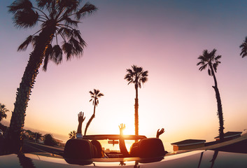Happy couple having fun during road trip in convertible car - Young lovers enjoying vacation in...