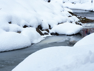 Mountain stream makes its way through the snowy channel